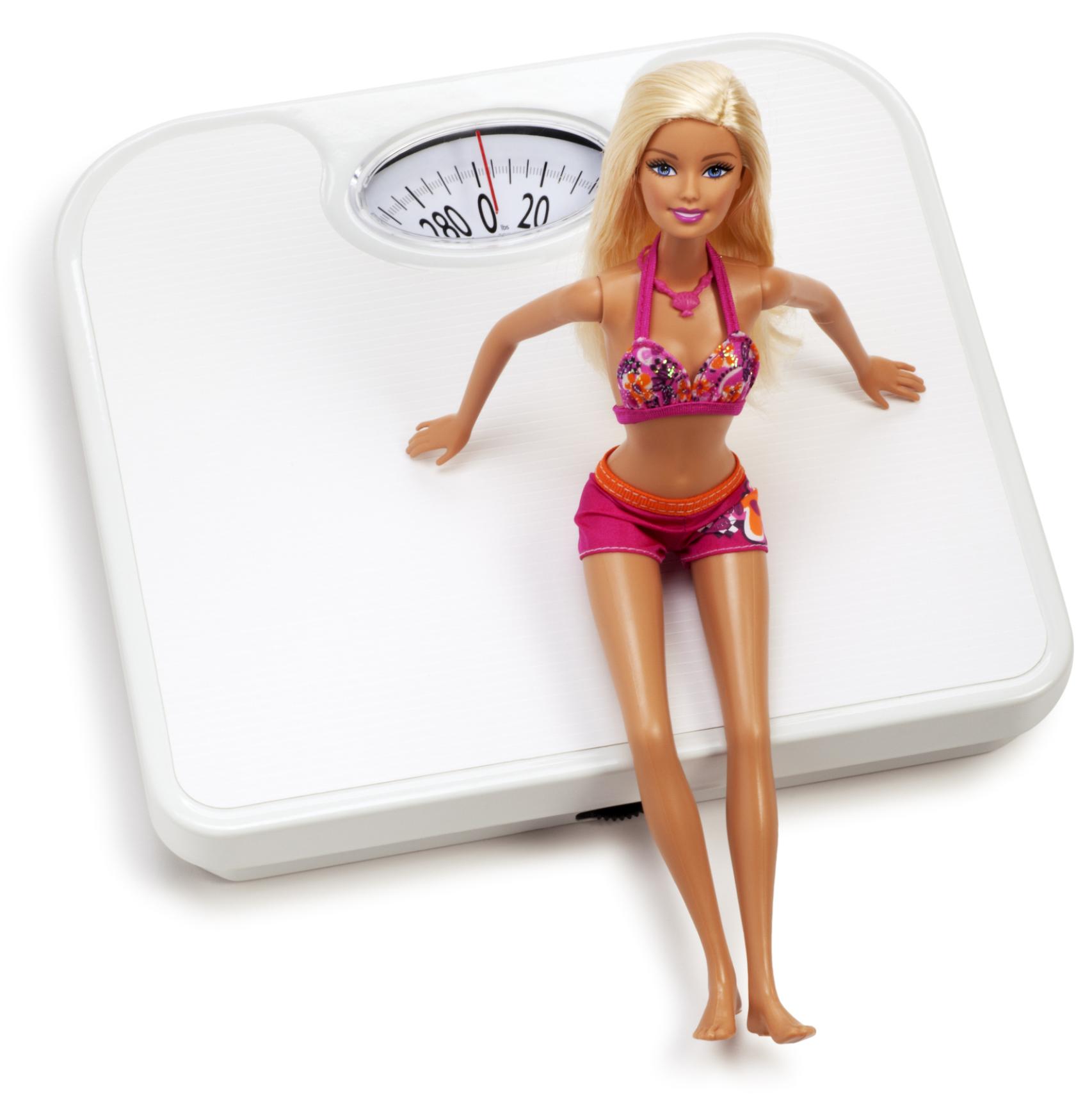 Muñeca Barbie sentada sobre una báscula.