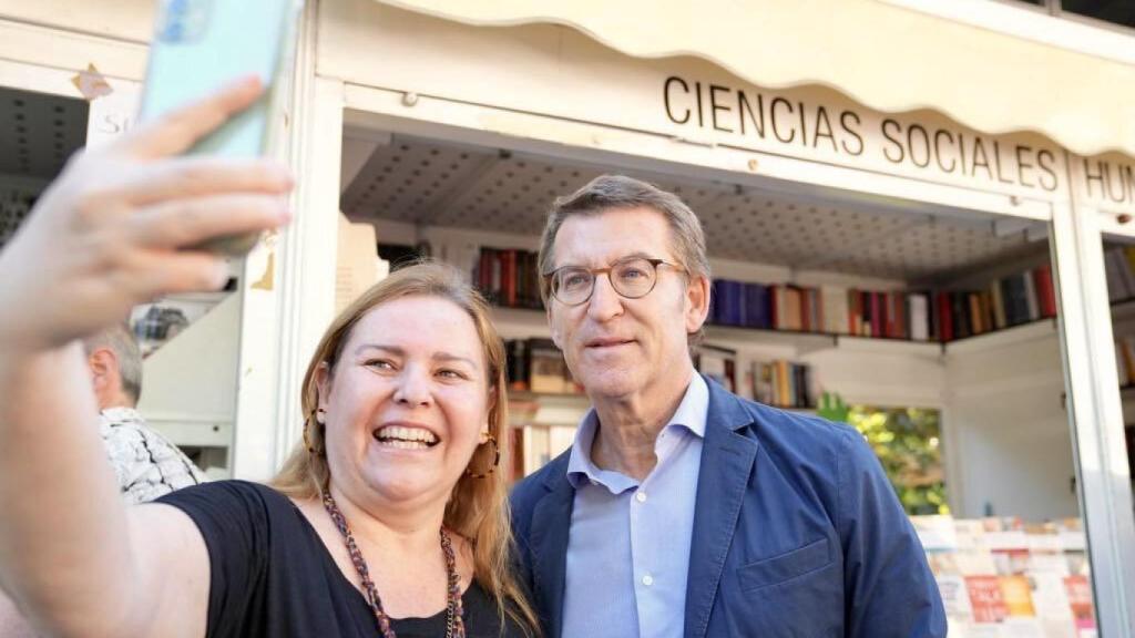 Alberto Núñez Feijóo posa junto a una ciudadana para una foto selfie en la Feria del Libro de Madrid.