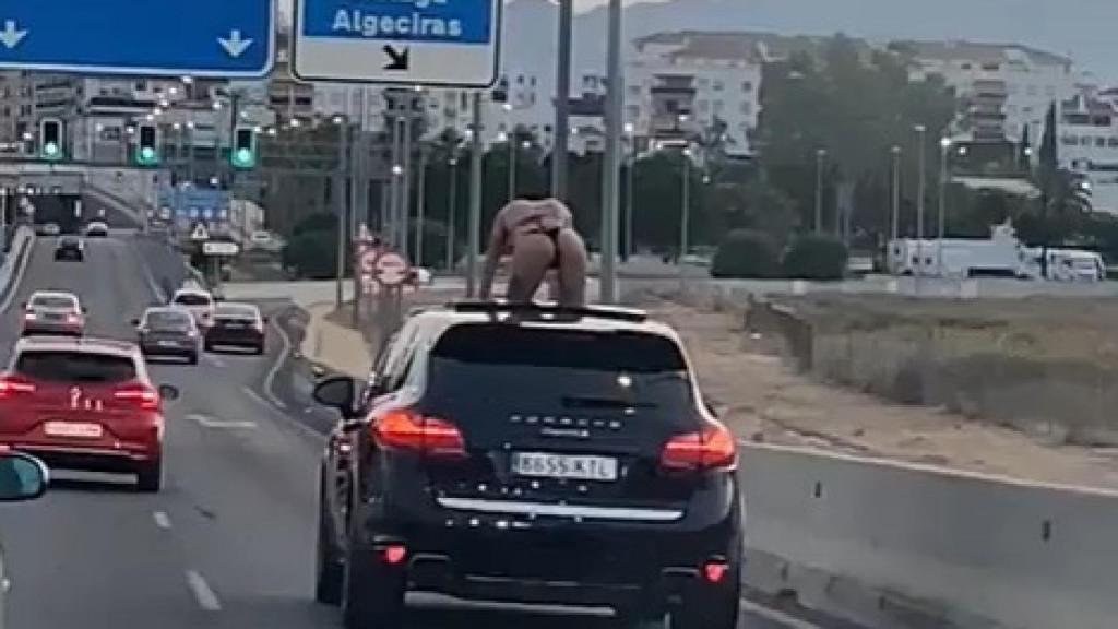 Una mujer sobre un coche en plena autovía.