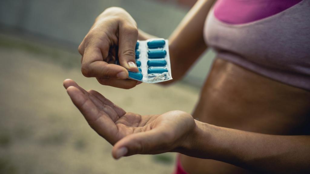 Una joven tomándose unas pildoritas.