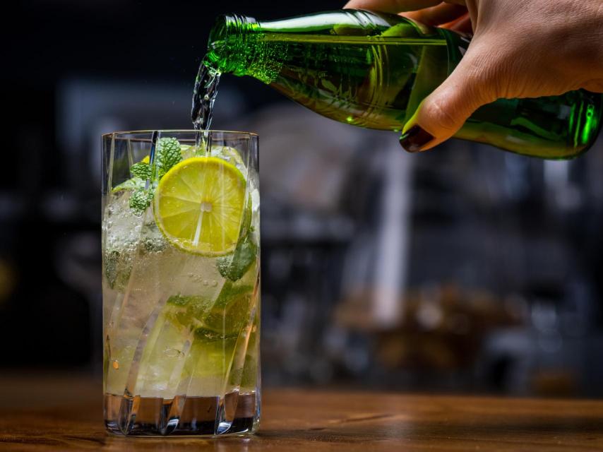 Una persona añade ginger ale a su cóctel.
