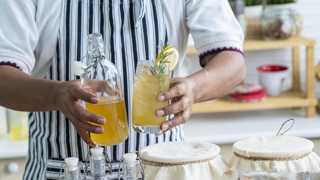Un hombre termina de servir una kombucha.