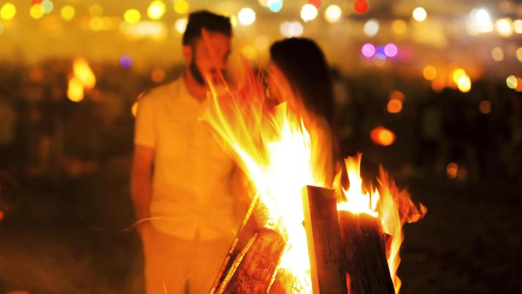 Imagen de archivo de una pareja de fondo en la playa durante las Hogueras de San Juan.