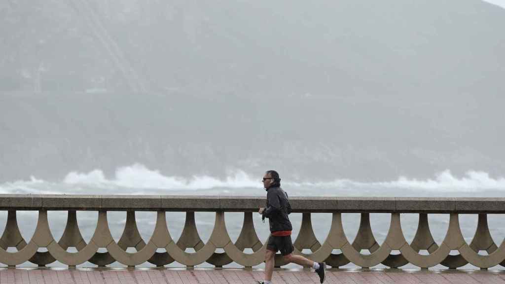 Un hombre, con chubasquero, corre por el Paseo Marítimo de A Coruña en una foto de archivo.