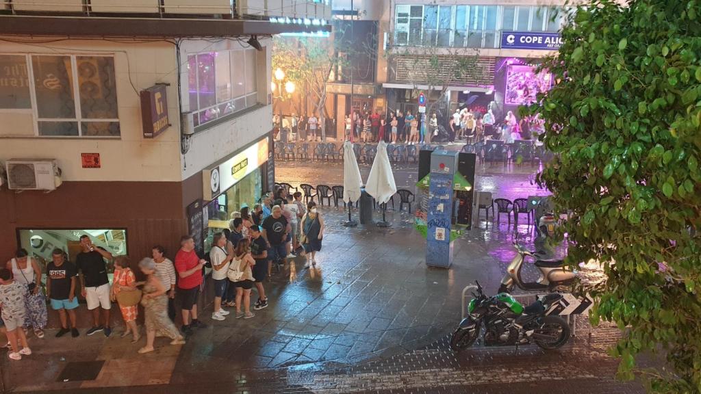 El público se refugia de la intensa lluvia que interrumpe el desfile de las comisiones de Hogueras.