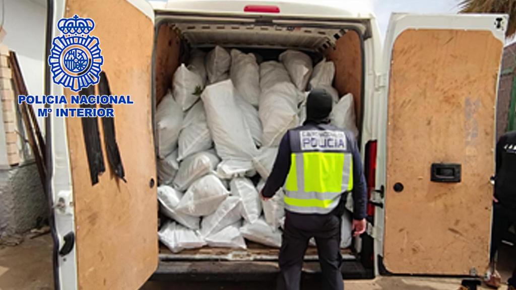 Un agente ante una furgoneta cargada con sacos de marihuana.