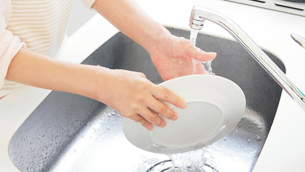 Una persona fregando los platos.