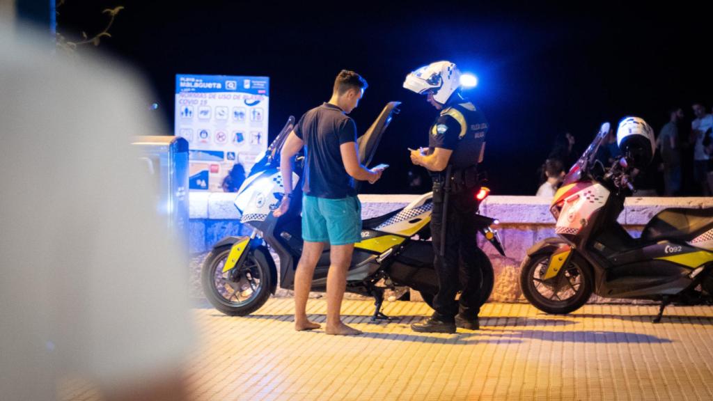 Un policía para a un joven en la noche de San Juan en Málaga.
