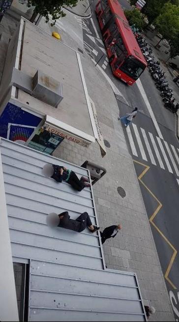 Las dos personas durmiendo sobre la marquesina del bus, desde uno de los edificios de la plaza