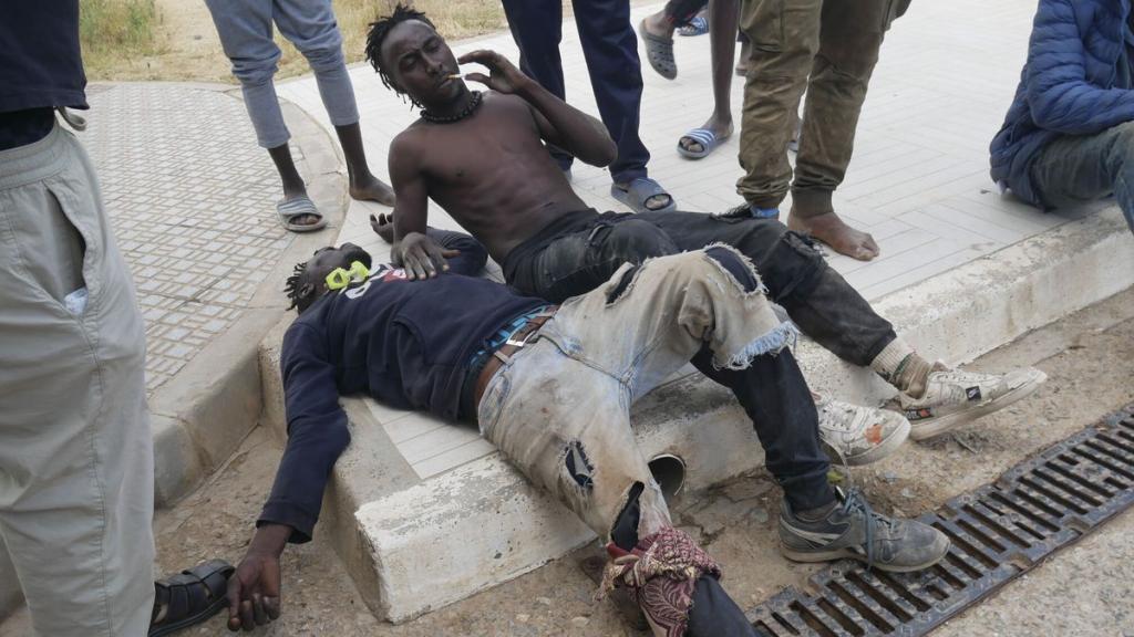 Dos de los migrantes, tras haber saltado la valla de Melilla.
