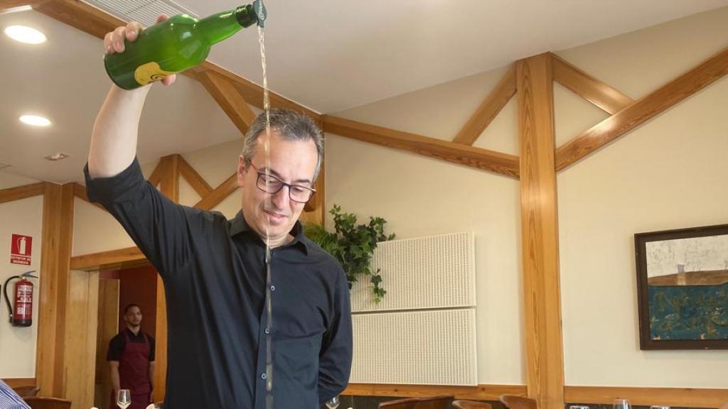 Tito echando sidra en un vaso.