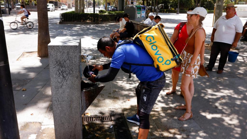 Un rider de Glovo refrescándose en una fuente durante la segunda ola de calor.