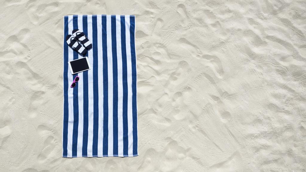 Vista superior de la playa con toalla y accesorios