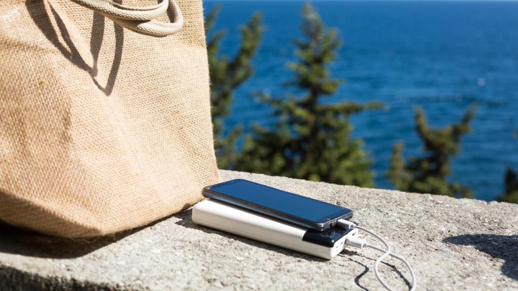 Móvil cargándose junto a un bolso de playa