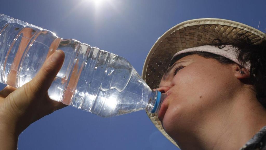 Una mujer bebiendo agua embotellada.