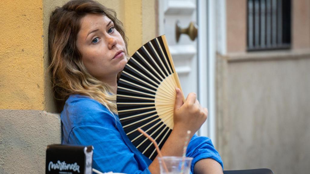 Una mujer se abanica en una terraza.