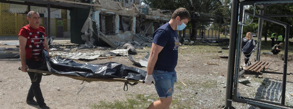Dos personas trasladan el cadáver de una de las víctimas del ataque ruso en Járkov.