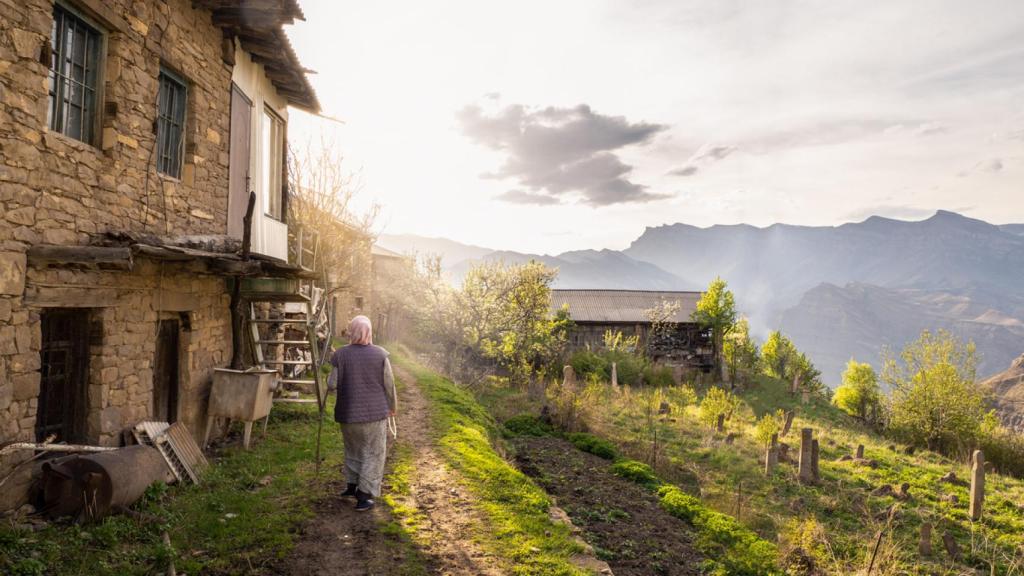 Una mujer camina por un pueblo montañoso.