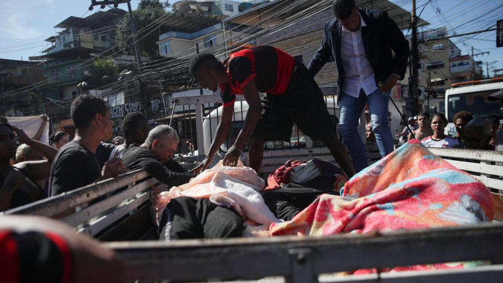 Los moradores de la favela subiendo los muertos a una furgoneta.
