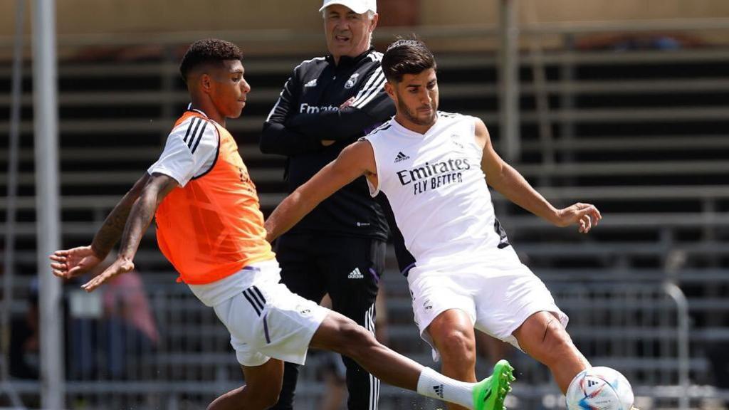 Marco Asensio juega un balón ante la mirada de Ancelotti