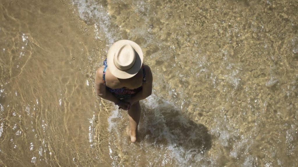Una mujer mayor paseando por una playa, en imagen de archivo.