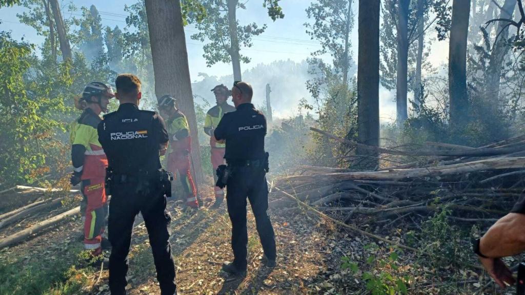 Agentes de la Policia Nacional junto con bomberos sofocando el incendio