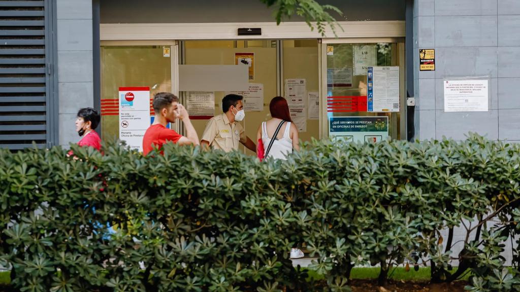 Varias personas a las puertas de una oficia de empleo.