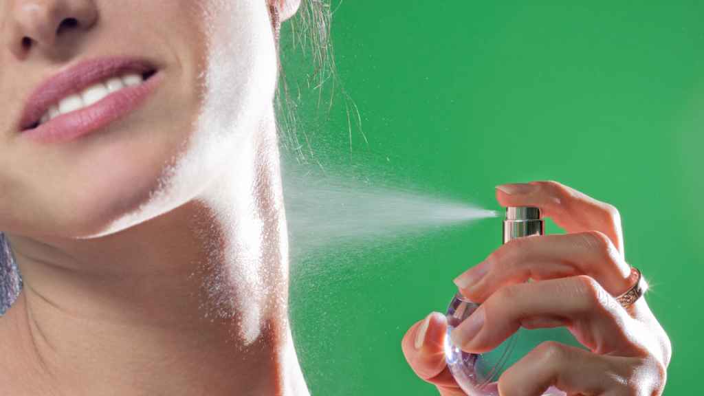 Mujer perfumándose el cuello.
