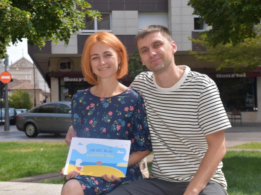 Kostiantyn y Olesia posan en la Plaza de San Miguel mostrando las ilustraciones del cuento de Alisa