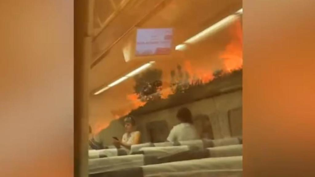 Pasajeros en el interior del tren rodeado de llamas.