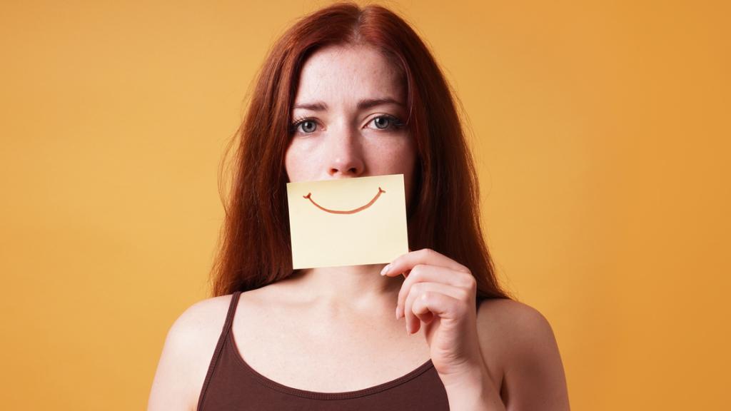 Mujer ocultando la tristeza tras una sonrisa.