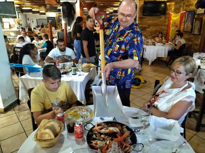 Pedro pone el himno de España mientras sirve el marisco.