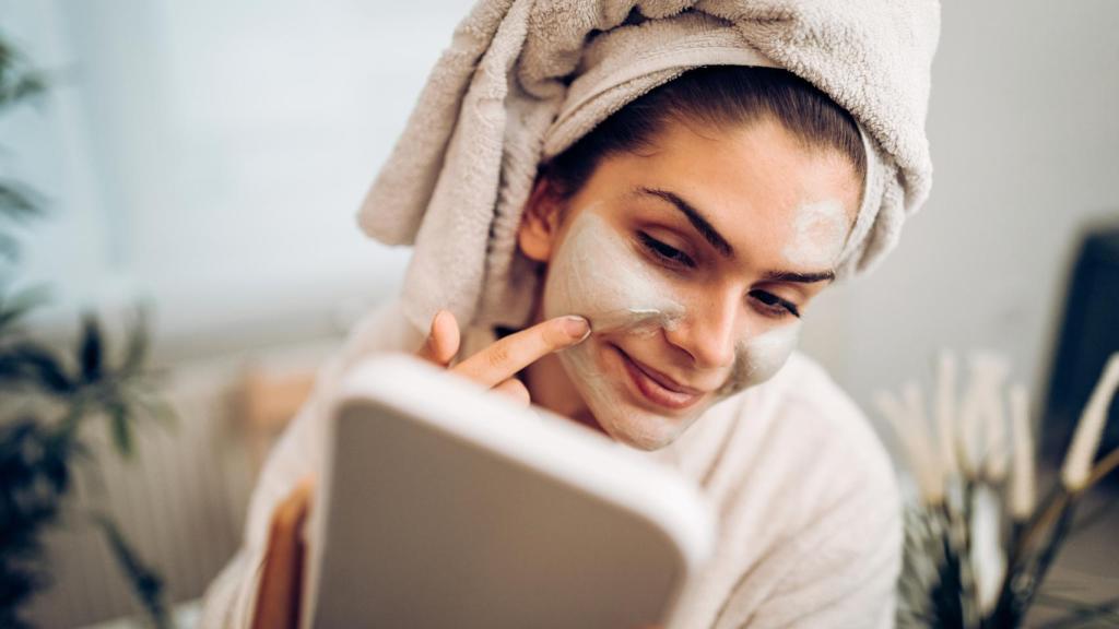 Una mujer se aplica una mascarilla en la cara.