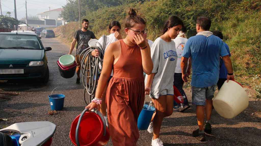 Varios vecinos de la parroquia de Meira (Moaña) con cubos de agua para sofocar el fuego.