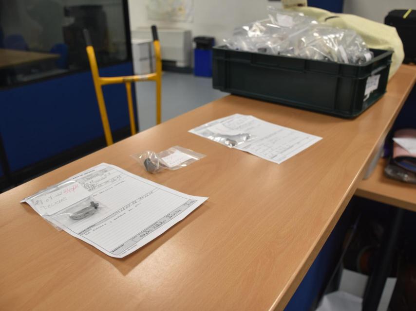 Varios audífonos y una caja con carteras en la Oficina de Objetos Hallados