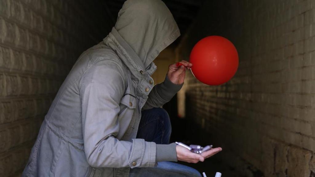 Un hombre con cartuchos de óxido nitroso, un sifón y un globo.