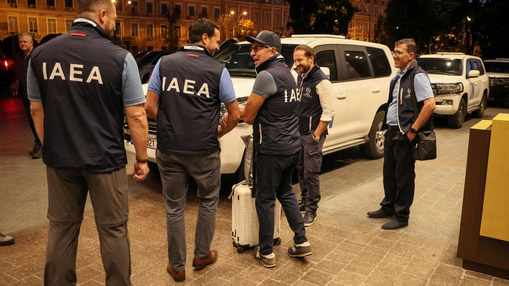 Los miembros de la misión del Organismo Internacional de Energía Atómica (OIEA) se encuentran junto a los vehículos de la ONU en el hotel cuando parten para visitar la planta de energía nuclear de Zaporizhzhia .