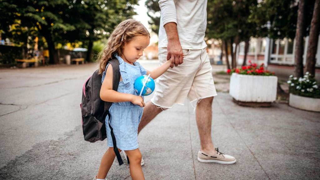 Niña llegando al colegio cogida de la mano de su madre