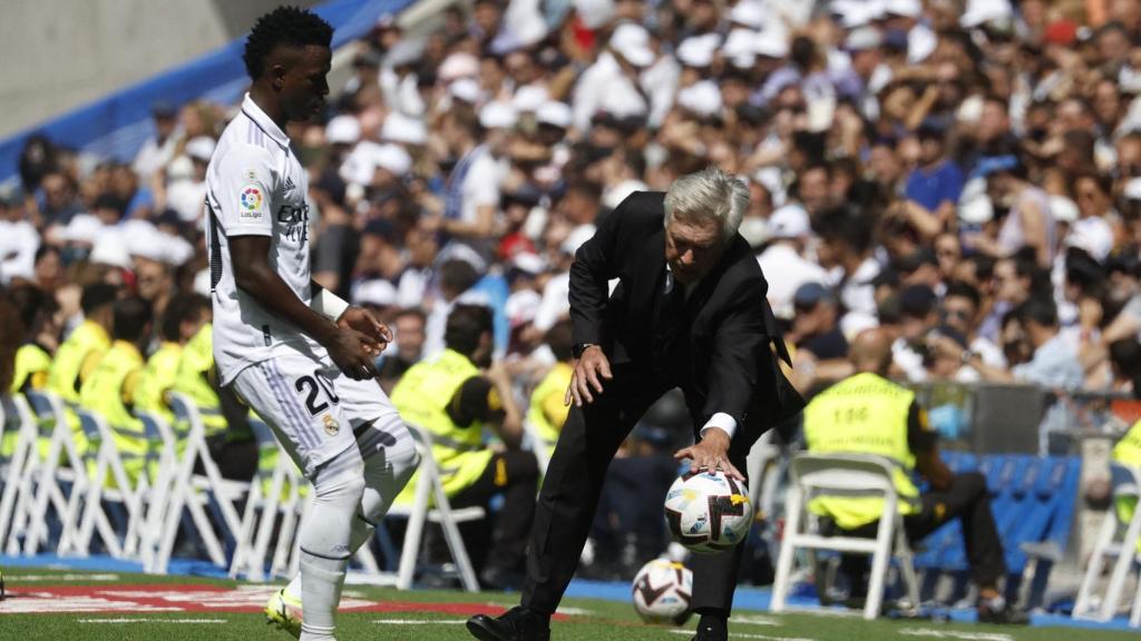 Carlo Ancelotti, recogiendo un balón con Vinicius esperando a su lado