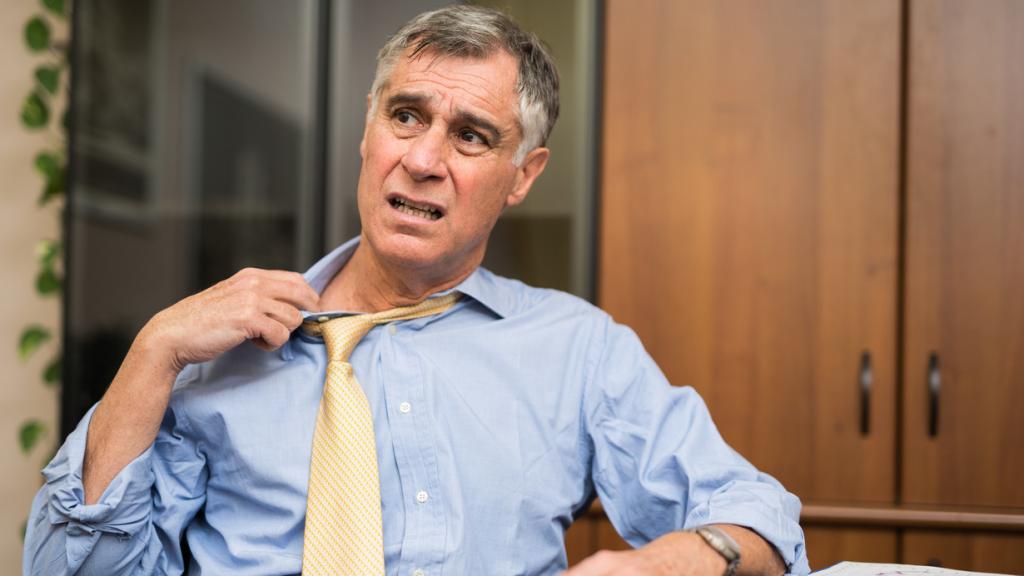 Imagen de archivo de un hombre pasando calor en la oficina.