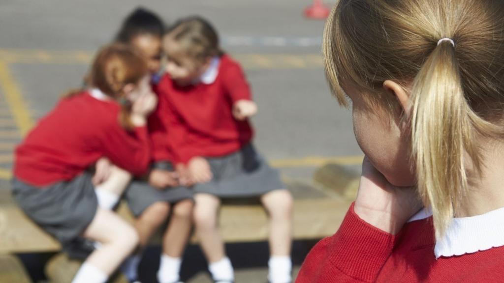 Tres niñas hablando sobre una compañera.