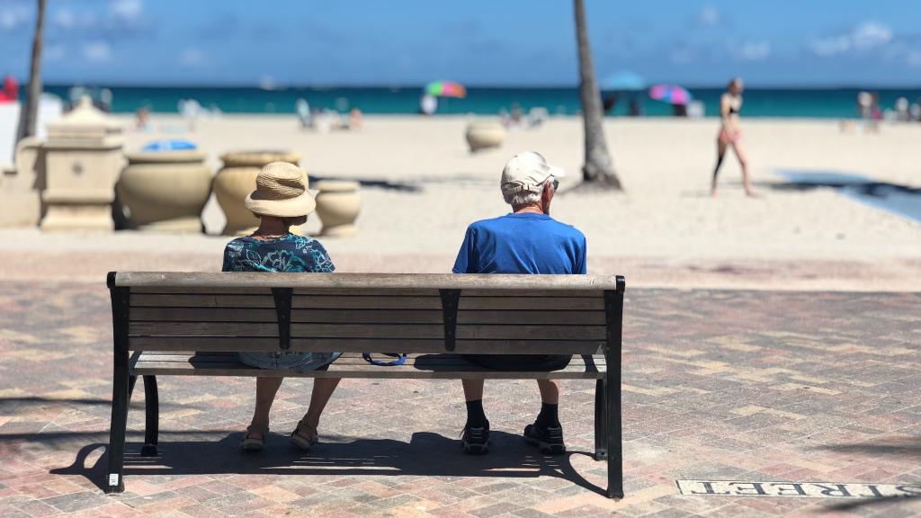 Dos jubilados sentados en un paseo marítimo.