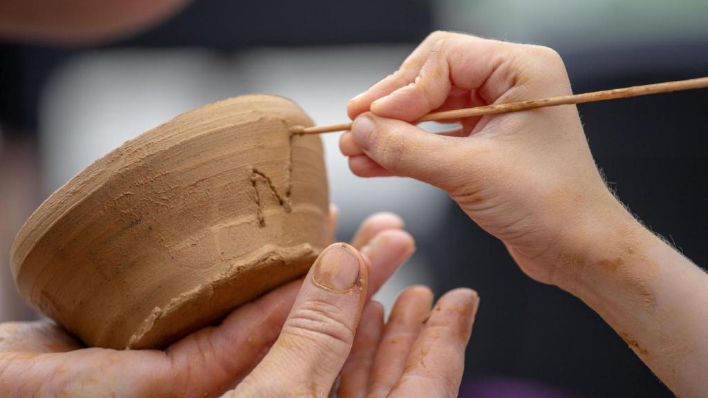 Niño haciendo un patrón en un tazón de arcilla.