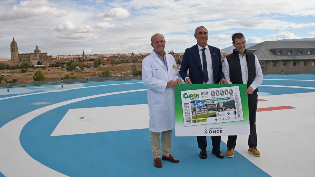 El delegado territorial de la Junta, José Mazarías, y el director de la Agencia ONCE en Segovia, Claudio Congosto, junto al gerente de Asistencia Sanitaria, Luis Gómez de Montes, presentando el cupón dedicado al Complejo Asistencial de Segovia