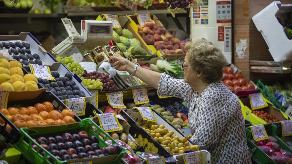 Una mujer compra en uno de los puestos del mercado de abastos de Triana, Sevilla.
