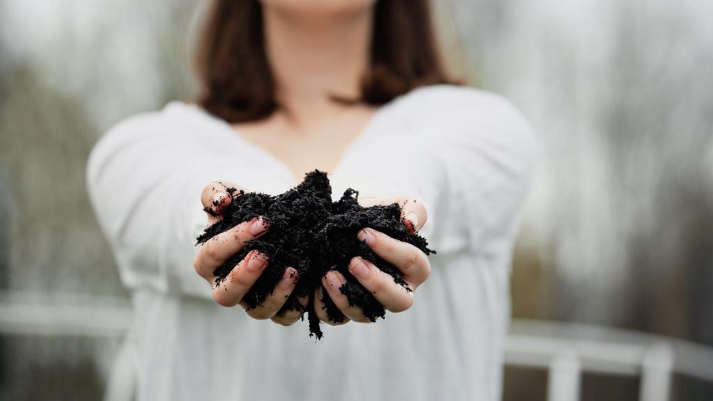 Imagen de archivo de una mujer cogiendo compost con las manos.