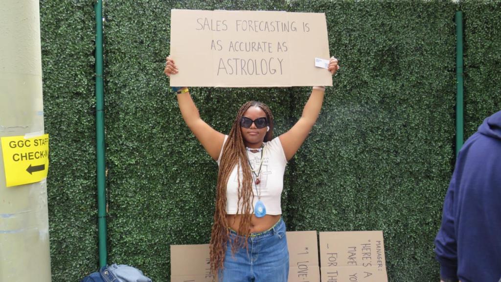 Una mujer sujetando una pancarta de marketing de guerrilla en los exteriores de Dreamforce 2022.