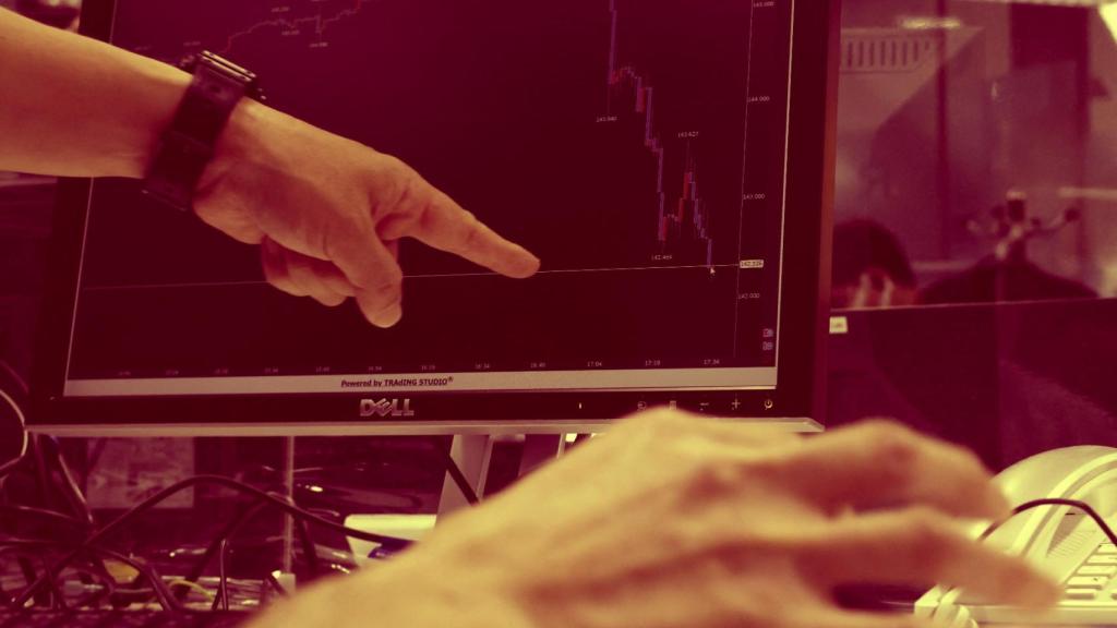 Dos operadores observan un gráfico de velas.