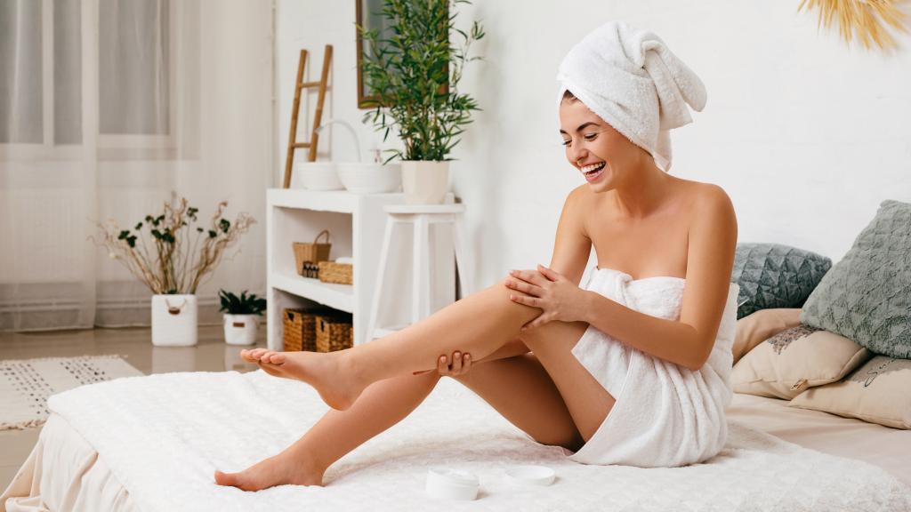 Una mujer aplicándose crema corporal.