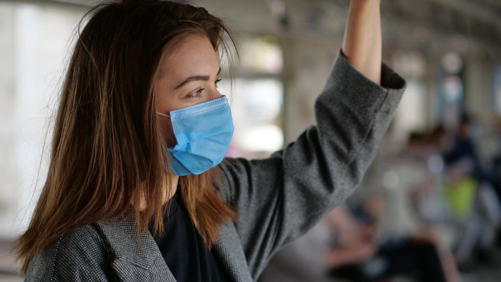 Imagen de una chica con mascarilla utilizando el transporte público